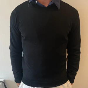 Svart tröja från Oscar Jacobson - Klassisk svart tröja från Oscar Jacobson i storlek S. Tröjan har rund halsringning och är långärmad, perfekt att bära över en skjorta för en clean och stilren look. Tillverkad i ett mjukt material som känns skönt mot huden. Aldrig använd, fick i present men tyckte den satt lite tajt på mig