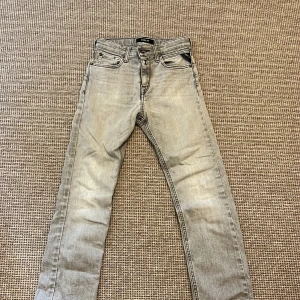 Replay ljusgrå jeans  - Snygga ljusgrå jeans från Replay, modell Thad. Klassisk femficksdesign med dragkedja och knapp, samt Replay-logga på fickan. Jeansen har raka ben och är tillverkade i mjukt denimtyg som ger en avslappnad vibe.