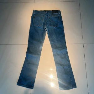 Blå bootcut jeans från Tiger Of Sweden - Snygga blå jeans från Tiger of Sweden med klassisk bootcut/strait -passform, lowrise. Jeansen har fem fickor, dragkedja och knapp framtill samt diskreta sömmar på bakfickorna. 