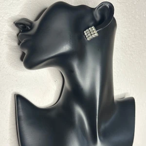 Vintage kristallörhängen i rutmönster – 50-talsglamour -  Stilfulla vintageörhängen från troligen 50-/60-talet i silverfärgad metall med klara kristaller i rutmönstrad design. Fina att bära till fest eller som glittrande detalj i vardagen. Ca 2 x 2 cm. Priset är redan lågt, så jag prutar inte – men jag erbjuder rabatt vid köp av flera saker. Jag rensar smyckesskrin och garderob, så kika gärna på mina andra annonser också! 