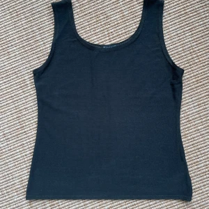 Mörkgrå topp från Sisters Point - En stilren mörkgrå topp från Sisters Point i storlek S/M. Toppen har klassisk rund halsringning och ärmlös design, perfekt att matcha med jeans eller kjol. 