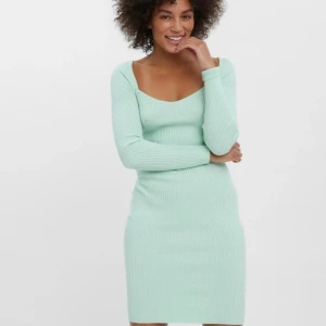 Mintgrön ribbad stickad klänning - Superfin mintgrön stickad klänning med ribbad struktur och lång ärm. Den har en snygg v-ringning och sitter tight mot kroppen för en fräsch och modern look. Perfekt för dig som gillar stilrena och bekväma outfits.