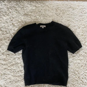 Svart stickad kortärmad tröja - En jättesöt, svart stickad tröja med korta ärmar🥰Tröjan har en enkel och clean look, perfekt till jeans eller kjol. Mjuk och skön känsla, passar de flesta! Tröjan är en S men är ganska stretchig så passar säkert fler! Säljer då den inte kommer till användning😗