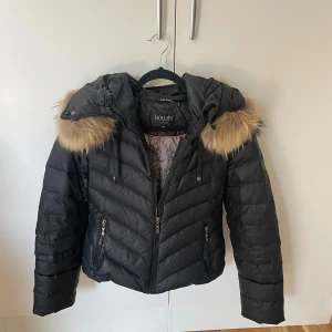 Svart vinterjacka med äkta päls från Hollies - Använd 1 säsong, i mycket gott skick  Äkta päls på luvan Avtagbar luva Nypris 5000