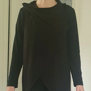 Svart omlottkofta från Stella Morgan - Svart långärmad kofta från Stella Morgan med omlottfront och draperad krage. Går att även ha som kofta.