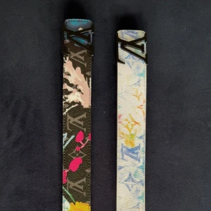 Louis Vuitton färgglada bälten välj 2st för 599 - Två smala bälten från Louis Vuitton med ikoniskt LV-spänne. Ena bältet har svart botten med färgglada blommor och logotyp, det andra har ljus bas med pastellfärgade LV-mönster och cirklar. Båda är i präglat skinn och har unika, konstnärliga tryck som sticker ut.
