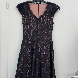 Svart spetsklänning från H&M XS - Supersnygg oanvänd svart spetsklänning från H&M i storlek XS. Klänningen har v-ringning, korta ärmar och ett nude-färgat foder som ger en cool kontrast. Blommigt spetsmönster och dragkedja bak.                   Hör av dig vid frågor!                                           Köparen står för frakten