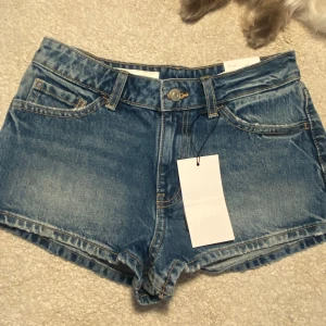 Blå jeansshorts från Zara - Snygga blå jeansshorts från Zara med klassisk femficksdesign och råa kanter. Shortsen är lowwaist och helt ny köpta. Kom privat för fler frågor 💕