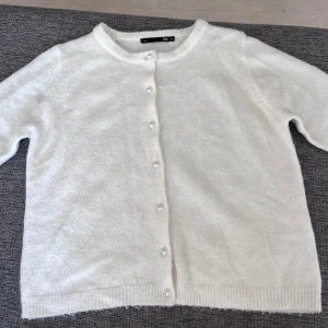 Vit kofta med pärlknappar XS - Superfin vit kofta från 157 i storlek XS. Koftan har korta ärmar, rund halsringning och pärlknappar framtill. Mjuk och lite fluffig känsla, perfekt att slänga över en topp. Passar dig som gillar en clean och söt stil. Den är använd fåtal gånger och nytvättad💓I fint skick💕 priset är Inte diskuterbart 