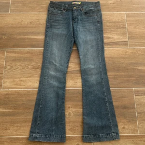 Lågmidjade utsvängda jeans  - Ett par lågmidjade jeans i storlek 40 (L). Rakt över midjemått: 39cm. Innebenslängd: 78cm. Total längd: 102cm. Gren: 19cm. Benslut: 23cm.  D33