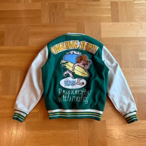 Grön och vit varsityjacka från Zara (strl Small) - Säljer denna snygga varsityjacka i grönt och vitt, köpt på Zara. Storlek Small. Den har coola broderade detaljer både fram och bak med texter som “Ongoing Shift”, “Reconnecting with reality” och surf-motiv på ryggen. Väldigt bekväm och perfekt nu till sommarkvällar eller hösten.  ✅ Inga stora defekter ✅ Använd få gånger, i fint skick ✅ Om du vill diskutera priset, skriv bara ✌️  Hör av dig vid frågor eller om du vill ha fler bilder!