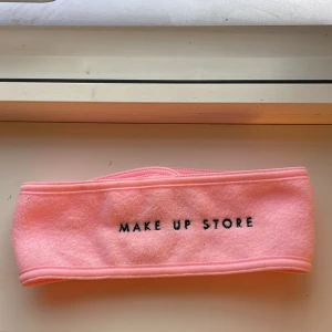 Rosa diadem från Make Up Store - Snyggt och mjukt rosa diadem från Make Up Store, perfekt för att hålla håret borta vid sminkning eller hudvård. Tillverkat i frotté med broderad svart text framtill och praktisk kardborreknäppning för enkel användning.