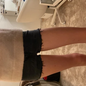 Svarta jeansshorts med fransig kant - Snygga svarta jeansshorts med rå, fransig kant nertill. Klassisk femficksmodell med låg midja och tight passform. Perfekta för varma dagar när du vill ha en chill och trendig look.