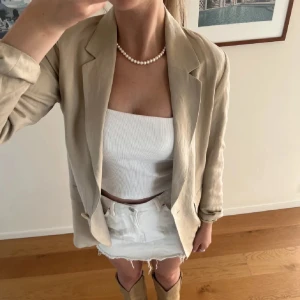 Beige linnekavaj från H&M - Beige kavaj från H&M i linneblandning. Klassisk passform med långa ärmar, slag och en knapp framtill. Två fickor framtill och helfodrad insida. 