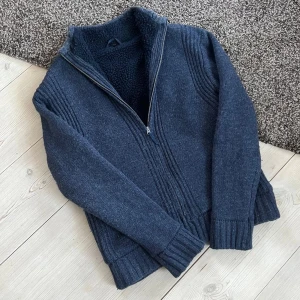 Fodrad Cardigan Stickad - Säljer denna snygga blå/grå fodrade cardigan i storlek M. Perfekt för att hålla värmen och samtidigt vara riktigt stilig. Perfekt skick, inga defekter!