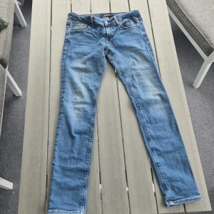  Replay jeans - Snygga blå jeans från Replay med klassisk femficksdesign och ljusa slitningar på låren. Perfekta för dig som gillar en stilren och modern look.