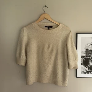 Beige stickad tröja från Vero Moda - Supermjuk beige stickad tröja från Vero Moda med rund halsringning och halvlånga puffärmar. Tröjan har ribbade muddar vid ärmslut och nederkant, vilket ger en snygg och enkel look. Perfekt att styla med jeans eller kjol för en chill vibe.