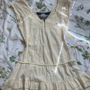 Cremefärgad vintage topp från Hilfiger denim  - vintage hilfiger topp med de sötaste detaljerna. Är i jättefint skick men har tyvärr inte kommit till användning. Är i ett lätt genomskinligt material. Står storlek XS men sitter rätt löst så passar förmodligen även lite större storlekar 