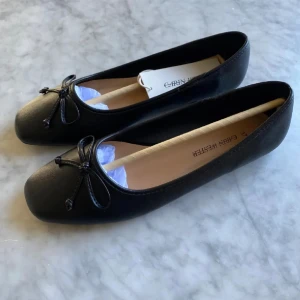 Svarta ballerinaskor med rosett, Carin Wester  - Fina ballerina skor från Carin Wester, de är helt oanvända då jag har ett annat par från ett annat märke. Nypris: 349 kr