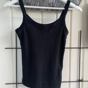 Svart ribbat linne från Gina Tricot - Ett ribbat linne från Gina Tricot, Basically Basics-kollektionen. Toppen har smala axelband, perfekt för lager-på-lager eller sommarens varma dagar. Enkel och stilren modell som är lätt att matcha med allt. <3