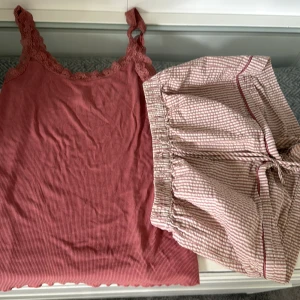 Rosa ribbad linnetopp med spets - Supersöt rosa linnetopp från Hunkemöller med ribbad struktur och breda spetsband. Toppen har en mjuk, feminin look och är perfekt för chill dagar eller som pyjamasöverdel. Matchar snyggt med randiga shorts i samma färgton. Endast annvänd tre gånger. 