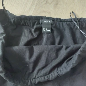 Svart enkel kjol från Lindex - Svart, rak och enkel kjol från Lindex i storlek M. Kjolen har resår i midjan och är tillverkad i mjukt bomullstyg. Perfekt för en clean och stilren look.