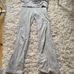 Grå yogapants från Gina Tricot - Superbekväma grå yogapants från Gina Tricot bootcut/utsvängda ben och mjukt material. Perfekta för chill dagar hemma eller när du vill ha en avslappnad look. Byxorna har en enkel design och är lätta att matcha med allt.