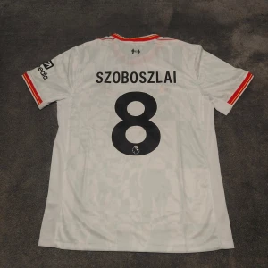 Liverpool FC | 24/25 | Szoboszlai | Size:L | Ny, oanvänd  - Liverpools tredjetröja för närvarande säsong 2024/25. Szoboszlai, nr 8 på ryggen. Storlek L. Helt ny & oanvänd. Stadium/fan edition. Tröjan är en nyproducerad reprint i utmärkt kvalitet.  Skickas 1-3 dagar efter mottagen betalning. Har du frågor/funderingar är det bara att höra av dig! :)