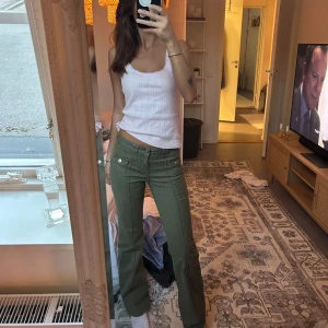 Olivgröna bootcut byxor med fickor - Snygga olivgröna byxor med bootcut-snitt och coola fickdetaljer framtill. Byxorna har låg midja och raka ben som blir lite utsvängda nertill. Perfekta för dig som gillar en avslappnad men ändå trendig look. Materialet känns mjukt och följsamt.