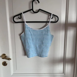 Randig ribbad linnetopp FB Sister - Säljer en söt ribbad linnetopp från FB Sister i storlek M. Toppen har smala axelband och är vit med ljusblå horisontella ränder. Perfekt för varma dagar och enkel att matcha med jeans eller shorts.