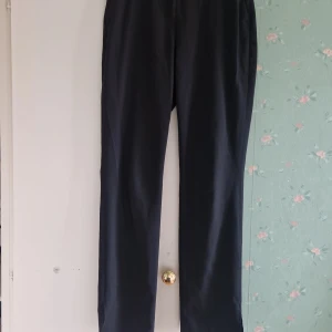 Svarta kostymbyxor - Snygga svarta kostymbyxor med en klassisk design. Byxorna har en rak passform och är perfekta för en stilren look. De har diskreta fickor baktill och en slitsdetalj vid benslutet.