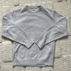 Säljer en stilren grå tröja från Zara. Den har en klassisk rund hals och långa ärmar med ribbade muddar. Perfekt för en avslappnad look. Passar bra till både jeans och chinos.