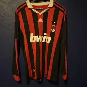 Gamal AC Milan tröja från Adidas - Säljer en klassisk AC Milan fotbollströja från Adidas i rött och svart med vit krage. Tröjan har långa ärmar och klubbmärke på bröstet. Perfekt för fotbollsfans som vill visa sitt stöd. 🖤❤️pris kan diskuteras 