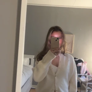 Vit kofta från Gina - Säljer en stilren vit kofta från Gina. Koftan har långa ärmar och knappar framtill. Perfekt för en avslappnad look. Passar bra till både jeans och kjol.