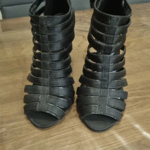 Svarta klackskor med remmar - Snygga svarta klackskor med remmar och öppen tå. Skorna har en dragkedja på baksidan för enkel på- och avtagning. Perfekta för en kväll ute eller en speciell tillställning.