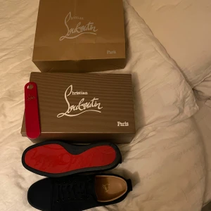 Blå skor från Christian Louboutin - Snygga svarta sneakers från Christian Louboutin med den ikoniska röda sulan. Skorna har snörning och en stilren design som passar perfekt för en trendig look. Bara höra av sig om du har fler frågor färgen är blå och inte svart 