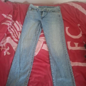 Blå jeans från H&M - Säljer ett par klassiska blå jeans från H&M i regular fit. De har en enkel design med fem fickor och en dragkedja. Perfekta för en avslappnad stil.