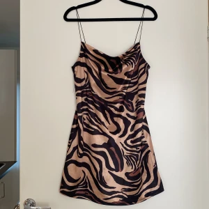 Zebramönstrad klänning från Zara - Snygg zebramönstrad klänning från Zara i beige och svart. Klänningen har tunna axelband och en cowl-neck. 