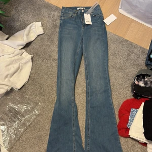 Blå bootcut jeans från NA-KD - Snygga blå bootcut jeans från NA-KD med medelhög midja. För stora för mig och därför säljer jag vidare. Storlek 32 i dessa. Endast provade. Alla lappar är kvar, kommer skickas i originalplasten. 💙
