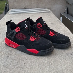 Svarta och röda Nike Air Jordans - Säljer ett par snygga Nike Air Jordans i svart och rött. Skorna har en ikonisk design med Jumpman-loggan på tungan och hälen. De är tillverkade i mocka med detaljer i syntet och har en bekväm passform med snörning.