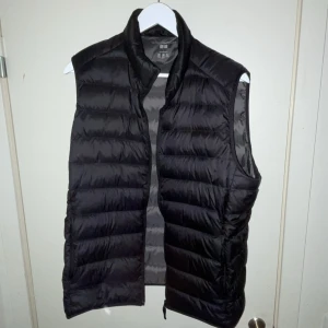 Svart dunväst från Uniqlo - Fin väst från Uniqlo som endast använts några gånger. Inget slitage, i nyskick. Köpt för 599kr