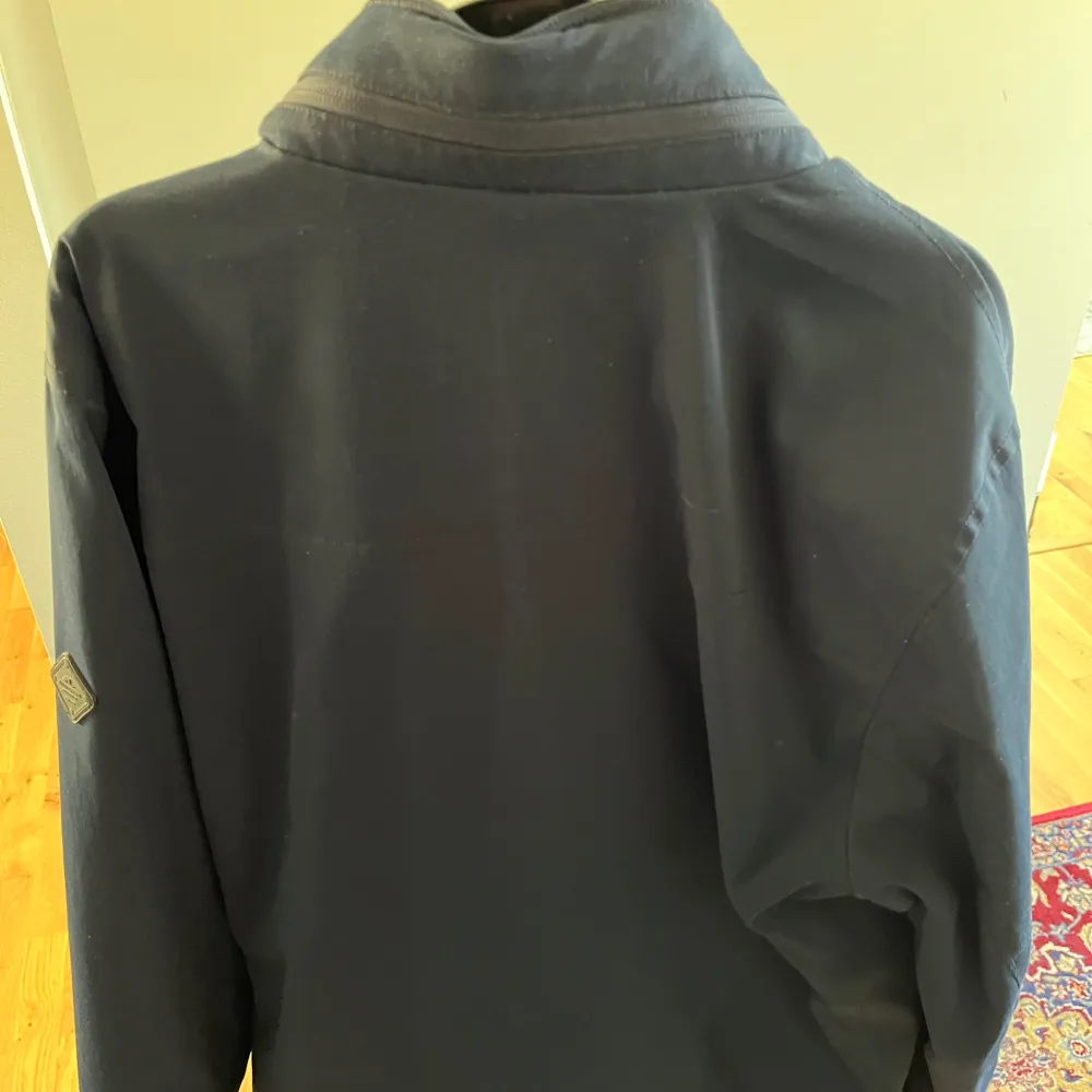 Snygg blå jacka från J.Lindeberg med dragkedja och knappar framtill. Jackan har två bröstfickor med knappstängning och en stilren design. Perfekt för en modern look.. Takit.