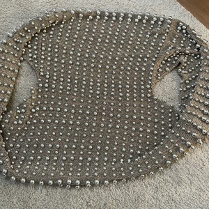 Beige tröja med pärlor - Säljer en beige tröja dekorerad med pärlor över hela ytan. Tröjan har en elegant design och är perfekt för att ge en extra touch till din outfit. Passar bra till både vardag och speciella tillfällen.