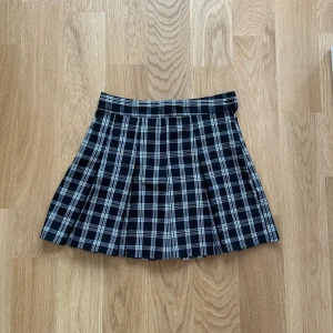 Kjol - Snygg rutig kjol från H&M i svart och vit. Kjolen har en klassisk plisserad design och är perfekt för en stilren look. Den är kort och passar bra till olika tillfällen. Knappast använt 💕
