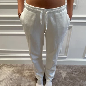Vita mjukisbyxor från Gina Tricot - Säljer ett par vita mjukisbyxor från Gina Tricot. Byxorna har en bekväm passform med dragsko i midjan och är perfekta för en avslappnad stil. Tillverkade i mjukt material för extra komfort.