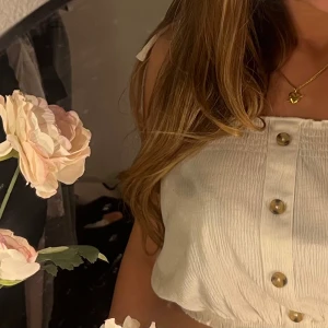 Vit croppad tubtopp från HM - Säljer en söt vit croppad tubtopp från HM med snörning. Toppen har knappar framtill. Perfekt till sommaren och passar storlek S storleksmässigt. 💌