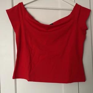 Röd offshoulder topp från BikBok - Säljer en snygg röd offshoulder topp från BikBok. Perfekt för en kväll ute eller en speciell tillställning. Toppen har en elegant design som framhäver axlarna.