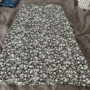 Svartvit blommig långkjol från Amisu - Supersnygg långkjol från Amisu i svart med vitt blommönster. Kjolen har en lätt utsvängd form och är gjord i ett tunt, flowy material som känns luftigt. Perfekt för dig som gillar en feminin och trendig stil med mycket mönster. Står 38 men sitter som en 36❤️