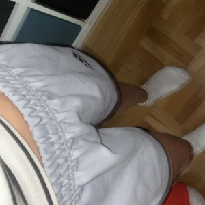 Grå sportshorts från Adidas M - Snygga ljusgrå sportshorts från Adidas med svart logga och svarta kanter. De har elastisk midja och är tillverkade i ett mjukt, syntetiskt material som passar perfekt för träning eller chill. Klassisk sportig look med kort modell och bekväm passform. Hoppas du gillade dom🥰🥰