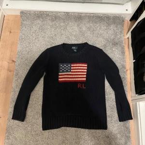 Mörkblå stickad tröja från Polo Ralph Lauren - 🇺🇸 Ralph Lauren Flaggsweater – XS/S (Unisex, Klassisk Ikon)  En riktig klassiker från Ralph Lauren med det broderade amerikanska flaggmotivet och “RL”-logga framtill – tidlös, preppy och cool i ett.  🧶 Passar XS/S – unisex modell 🧼 Inga fläckar, i fint skick 💯 Äkta Ralph Lauren-kvalitet 🔥 Mjuk och kraftig bomullsstickning – perfekt för både höst och vår  En tröja som funkar till allt – dressa upp eller ner, den gör alltid jobbet. Sällsynt i så här fint skick – missa inte!  📬 Snabb leverans 💬 Bud 